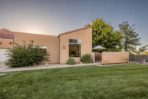 Back of house with a lawn, a gate, fence, and stucco siding