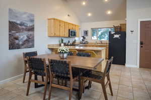 Dining area with baseboards, high vaulted ceiling, visible vents, and light tile patterned floors