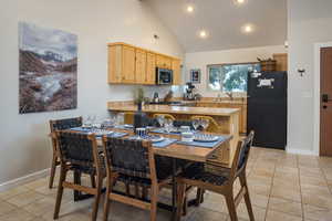 Dining area featuring light tile patterned flooring, high vaulted ceiling, and baseboards