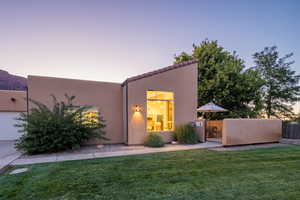 Back of property featuring a yard, a gate, stucco siding, and fence