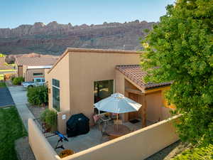Rear view of property featuring stucco siding, fence, a tiled roof, a mountain view, and a patio area