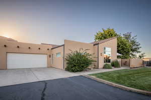 View of front of property featuring a tiled roof, concrete driveway, stucco siding, and an attached garage