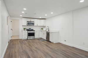 Kitchen with dark wood-type flooring, white cabinetry, a sink, and stainless steel appliances