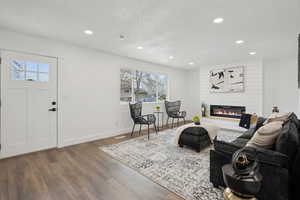 Living area featuring recessed lighting, baseboards, a textured ceiling, a large fireplace, and wood finished floors