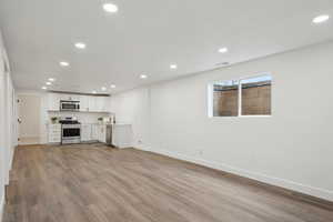 Kitchen featuring light countertops, white cabinetry, wood finished floors, stainless steel appliances, and recessed lighting
