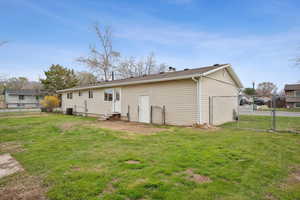 Back of property featuring a lawn, a gate, fence, and entry steps