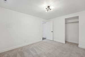 Unfurnished bedroom featuring carpet, baseboards, a textured ceiling, visible vents, and a closet