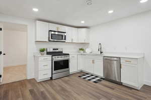 Kitchen featuring white cabinets, a sink, stainless steel appliances, and light countertops