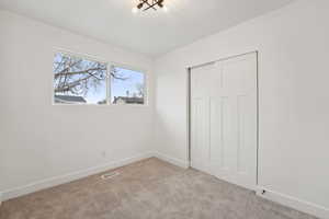 Unfurnished bedroom with carpet floors, a closet, baseboards, and visible vents