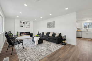 Living room with baseboards, visible vents, wood finished floors, and a large fireplace