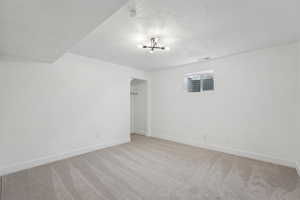 Unfurnished room featuring visible vents, baseboards, light colored carpet, and a textured ceiling