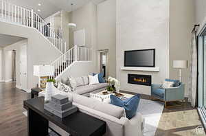 Living room with stairs, a high ceiling, a fireplace, and wood finished floors