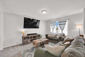 Carpeted living area featuring baseboards and visible vents