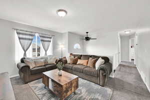 Carpeted living room featuring baseboards and ceiling fan