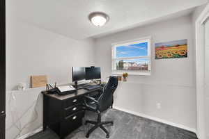 Carpeted office with baseboards and a textured ceiling