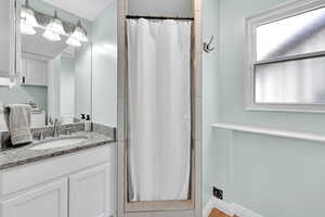Bathroom featuring baseboards, curtained shower, and vanity