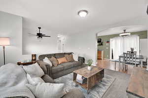 Living area with wood finished floors, arched walkways, baseboards, and ceiling fan