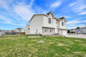 Exterior space with fence, an attached garage, concrete driveway, brick siding, and a front lawn