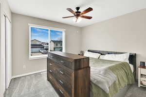 Bedroom featuring baseboards, a ceiling fan, and light colored carpet