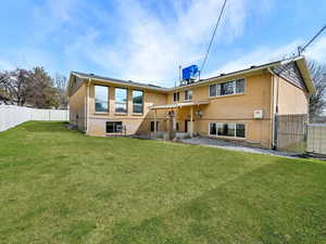 Back of house with brick siding, fence, and a yard