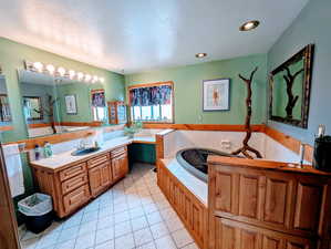 Bathroom with tile patterned flooring, vanity, recessed lighting, a textured ceiling, and a bath