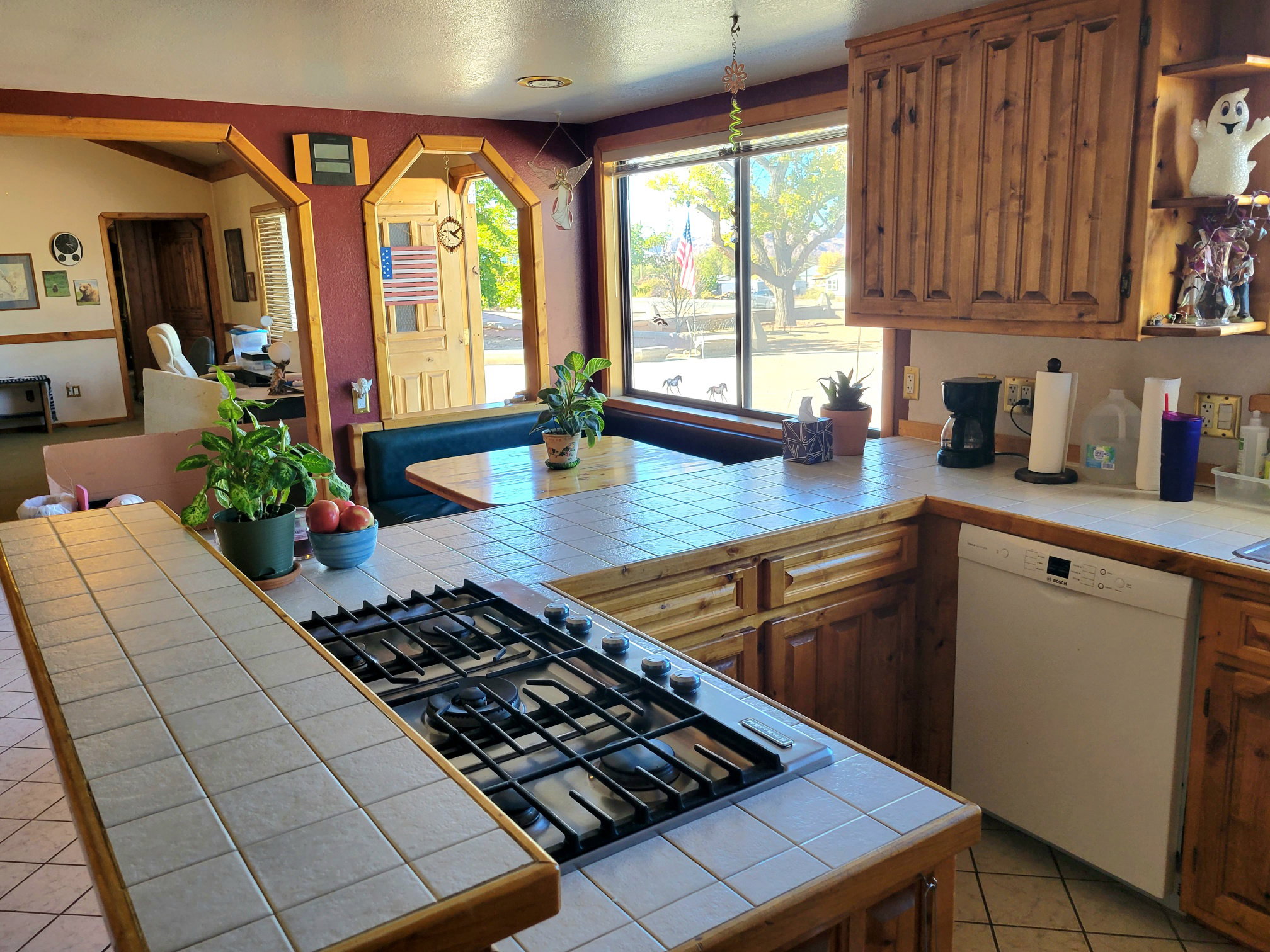 Kitchen with tile counters, white dishwasher, stainless steel gas cooktop, and arched walkways