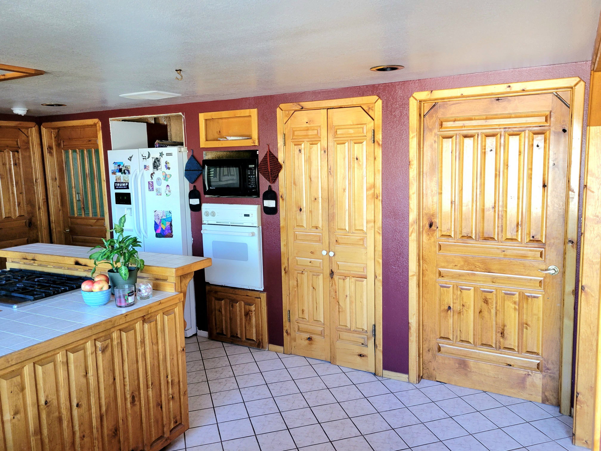 Kitchen with tile counters, white appliances, and light tile patterned flooring