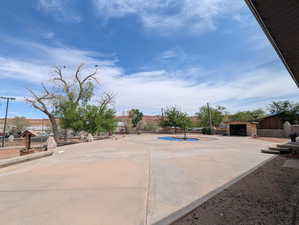 View of patio with a fenced in pool, a garage, fence, and an outbuilding