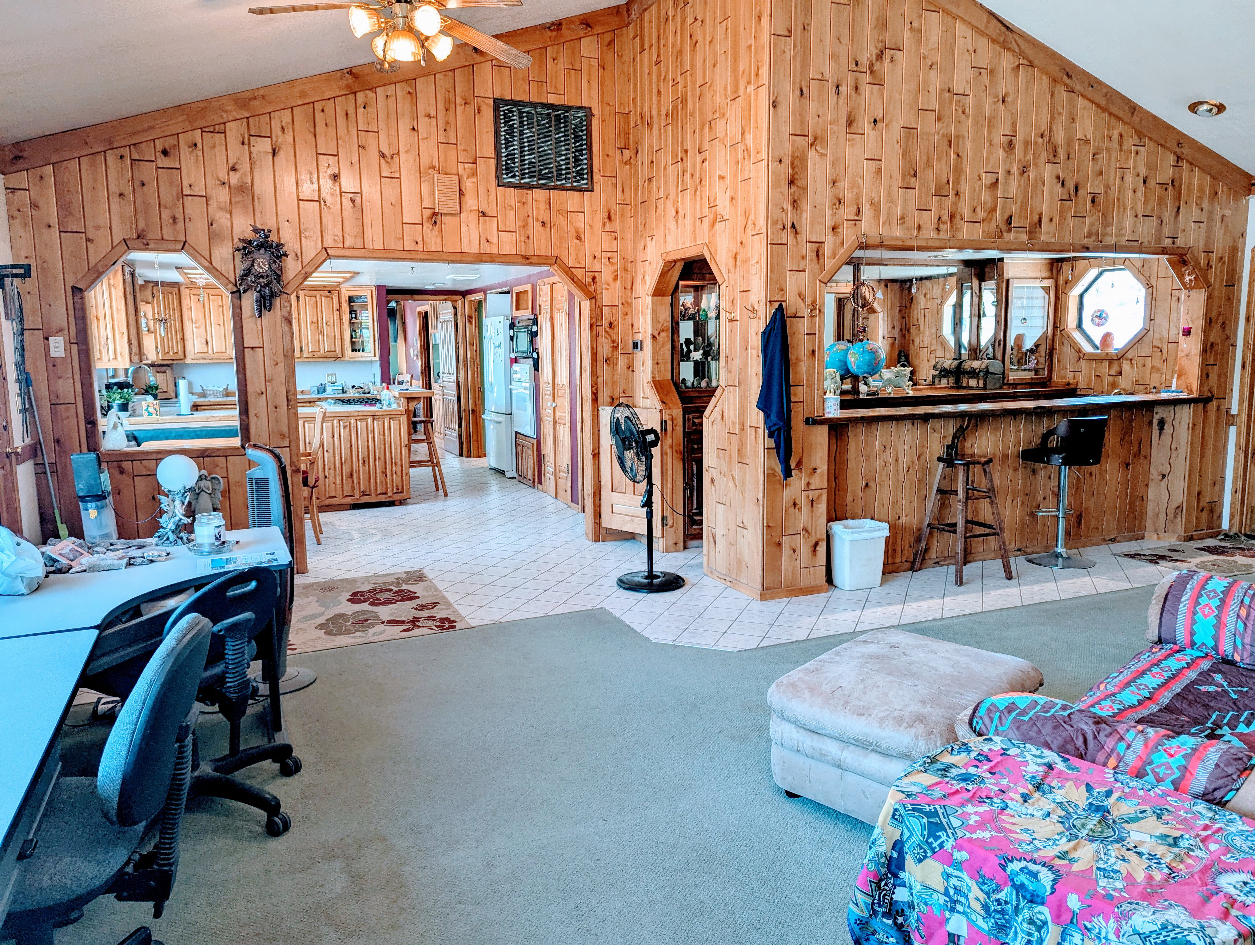 Vaulted ceiling, wooden walls, ceiling fan, and carpet