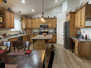 Kitchen with a sink, open shelves, appliances with stainless steel finishes, a center island, and brown cabinetry