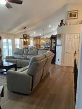 Living area featuring dark wood finished floors, vaulted ceiling, ceiling fan, and recessed lighting