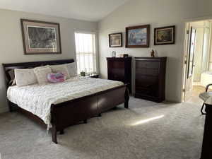 Bedroom with light carpet, connected bathroom, baseboards, and vaulted ceiling