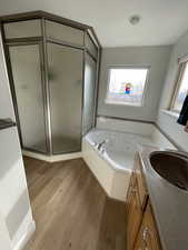 Full bathroom with a stall shower, a tub with jets, wood finished floors, and vanity