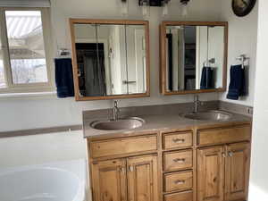 Full bath with a spacious closet, double vanity, a sink, and a bathtub