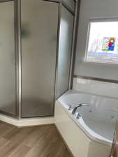 Bathroom featuring a shower stall, a whirlpool tub, and wood finished floors