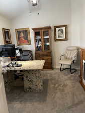 Carpeted home office with baseboards, lofted ceiling, a ceiling fan, and a fireplace