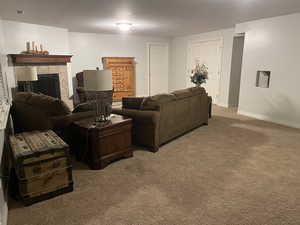 Carpeted living area featuring a tiled fireplace, baseboards, and visible vents