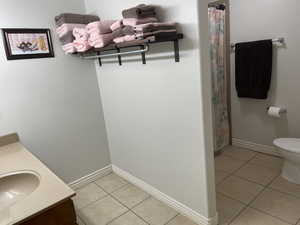 Bathroom featuring tile patterned flooring, vanity, toilet, and baseboards