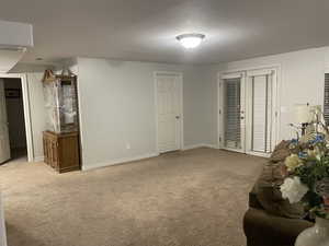 Living area with baseboards, visible vents, and light carpet