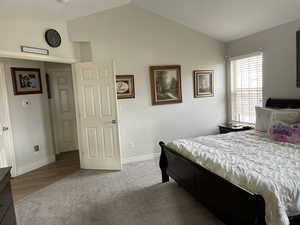Carpeted bedroom featuring baseboards and vaulted ceiling