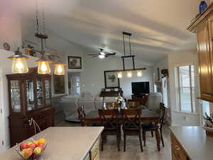 Dining space with light wood-style flooring, vaulted ceiling, and a ceiling fan