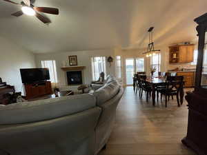 Living room with light wood finished floors, vaulted ceiling, and ceiling fan