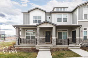 View of front of home featuring stone siding, board and batten siding, and covered porch