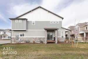 Side of house with a lawn, stone siding, board and batten siding, and a residential view