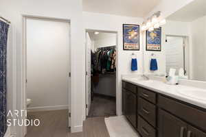 Bathroom featuring double vanity, a sink, toilet, and a spacious closet