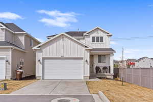View of front of home featuring fence, an attached garage, concrete driveway, board and batten siding, and roof with shingles