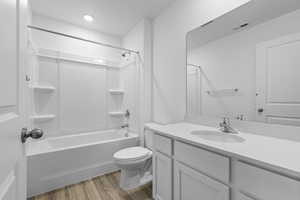 Full bath featuring visible vents, washtub / shower combination, wood finished floors, toilet, and vanity