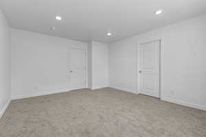 Carpeted spare room featuring baseboards, a textured ceiling, and recessed lighting