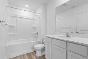 Full bathroom featuring visible vents, toilet, wood finished floors, vanity, and shower / bathtub combination