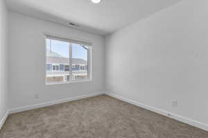 Carpeted spare room with a textured ceiling, baseboards, and visible vents